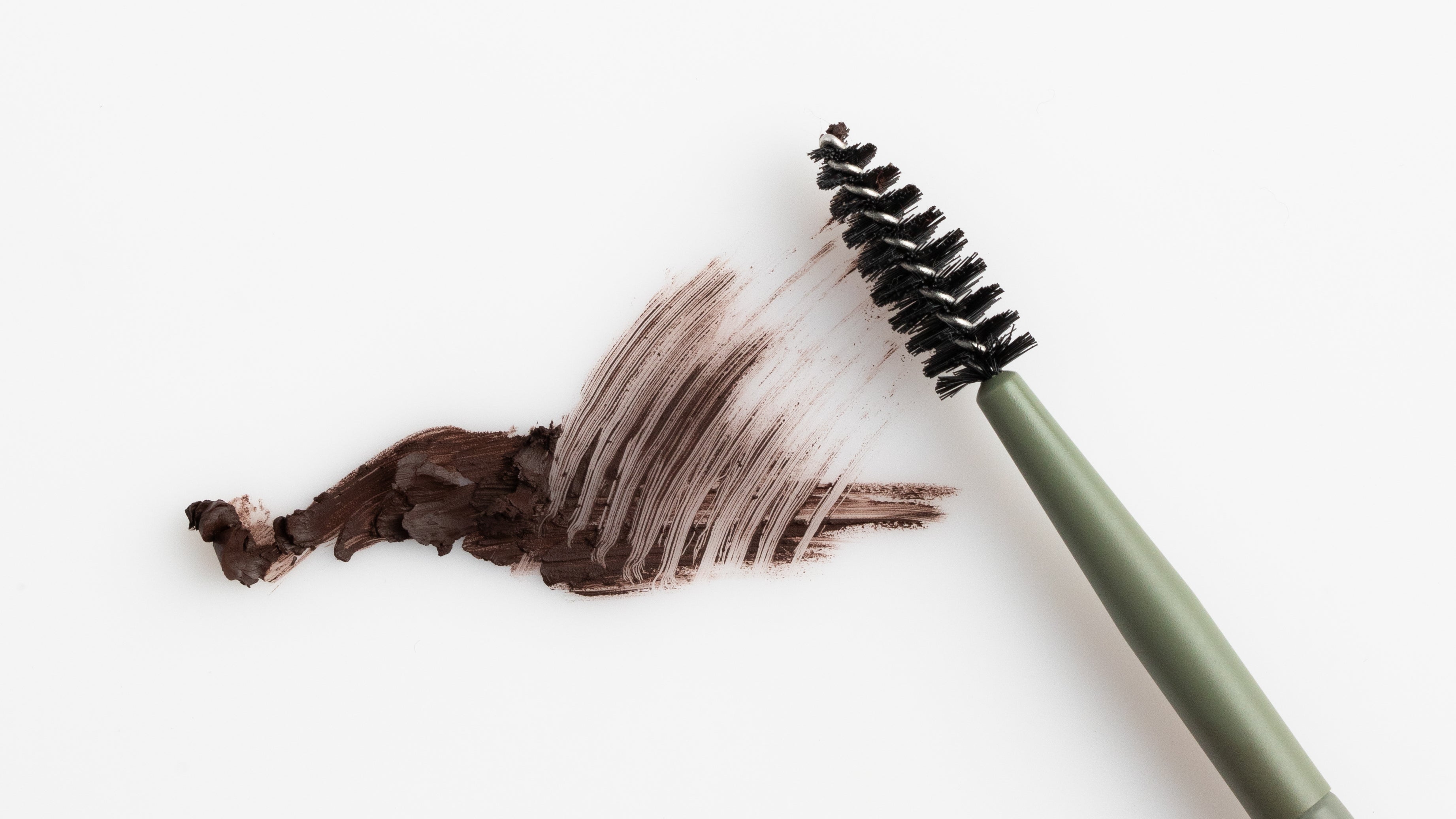 brow brush smearing brow pencil swatch on white background