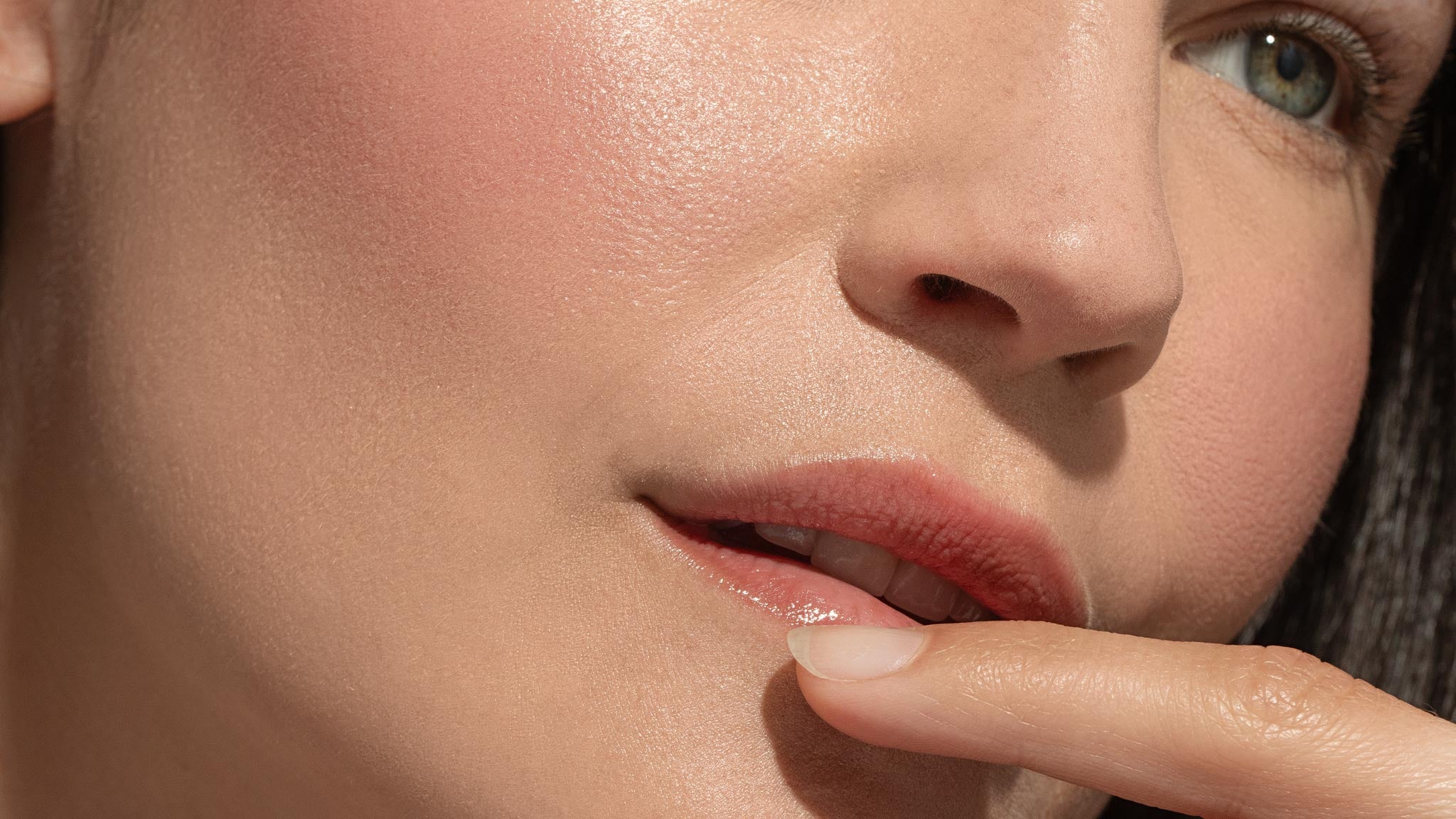 Close-up of a person's lips with a finger touching them